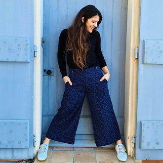 Femme portant le Pantalon - Short Deauville - T34 à 48, patron de couture pdf à télécharger, élégante et moderne devant une porte bleue.