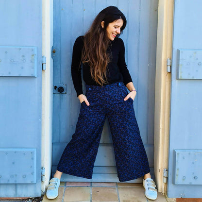 Femme portant le Pantalon - Short Deauville - T34 à 48, patron de couture pdf à télécharger, élégante et moderne devant une porte bleue.