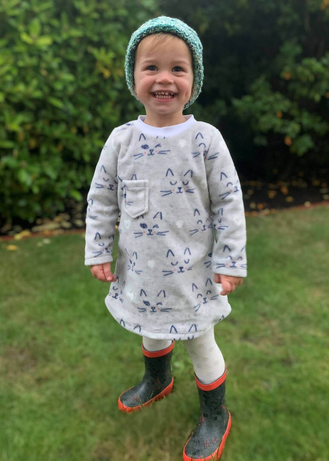 Enfant souriant portant une Robe Sweat Mini-MILA pour filles du 2 au 16 Ans, patron de couture pdf à télécharger, avec motif félin.