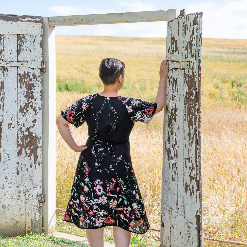 Person wearing Robe blouse portefeuille, 34 au 56, 4 statures – Sésame, patron de couture pdf à télécharger, in a field.