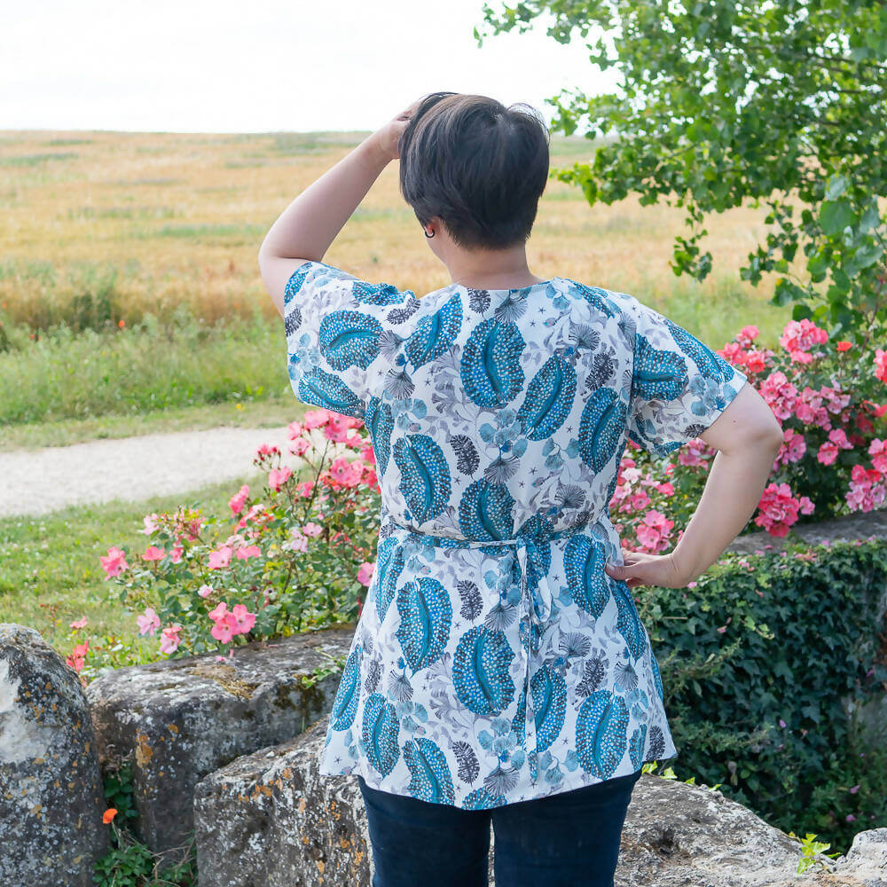 Vue arrière de la robe blouse portefeuille, 34 au 56, 4 statures – Sésame, dans un jardin fleuri, patron de couture pdf à télécharger.