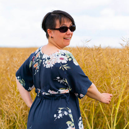 Femme portant la Robe longue 34 au 52, 4 statures, patron débutant – Wasabi dans un champ, vêtement avec manches kimono.