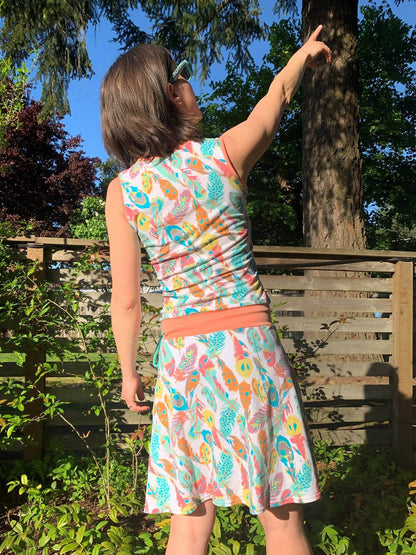 Femme portant SANDY - La robe cache-coeur pour femmes du 34 au 54 en tissu imprimé coloré dans un jardin, patron de couture pdf à télécharger.