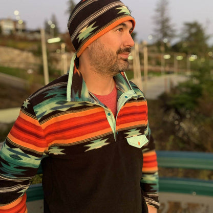 Homme portant un sweat à motifs colorés en extérieur, assorti d'un bonnet, pour présenter SHERPA - La polaire mixte du XS au XXXL.