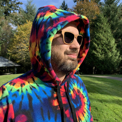 Homme portant un sweat à capuche tie-dye vibrant en forêt, lunettes de soleil
