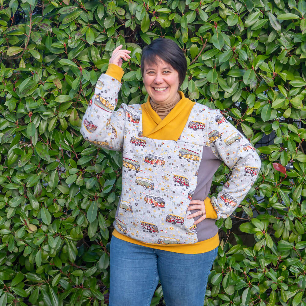 Sweat mixte, XS au 4XL, 2 statures – Anis, avec col croisé original, présenté par une femme devant des plantes. Patron de couture pdf à télécharger.