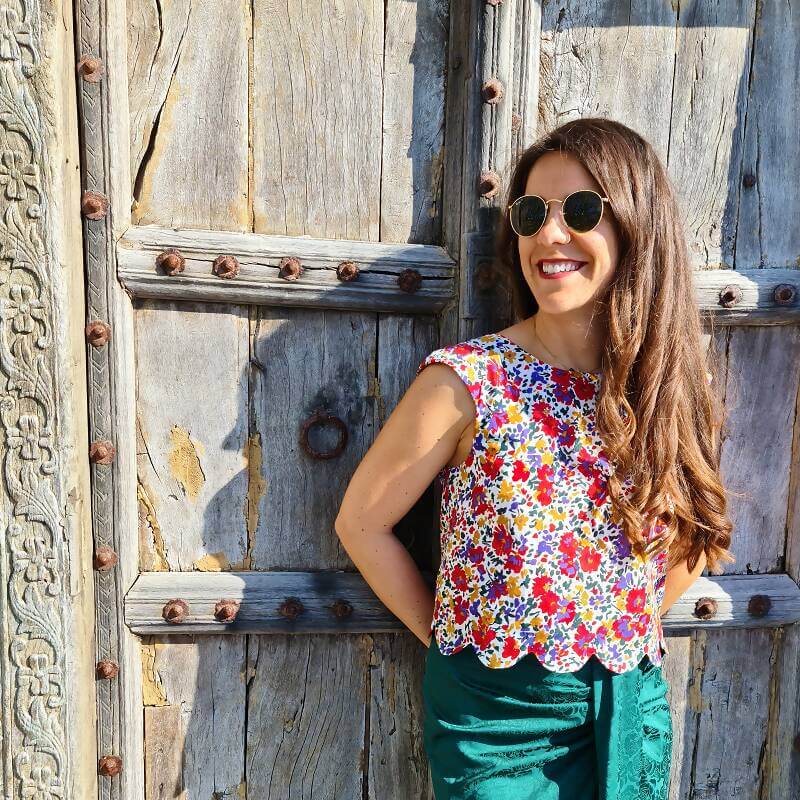 Femme portant le Top Fleury - T34 à 48, style estival coloré, patron de couture pdf à télécharger, sur fond de porte ancienne.