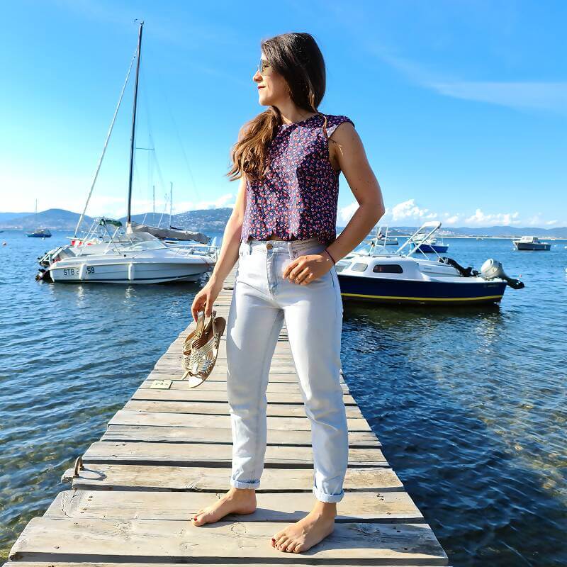 Femme portant le Top Fleury - T34 à 48 sur un ponton, entourée de bateaux, ciel bleu et mer en arrière-plan. Patron de couture PDF à télécharger.